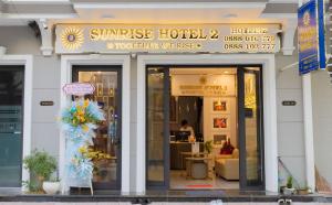 Bạc LiêuSUNRISE Hotel Bạc Liêu的窗户上有鲜花的酒店前方的商店