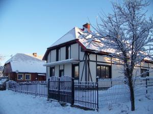 JeżyceAgroturystyka W Jabłoniowym Sadzie的雪中带围栏的白色房子