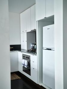 墨尔本Chic Urban Loft in Prime Location的白色的厨房配有白色橱柜和冰箱。