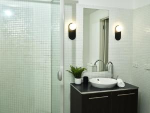 墨尔本Chic Urban Loft in Prime Location的一间带水槽和玻璃淋浴的浴室