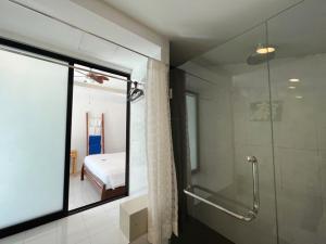 奈扬海滩The Snug Airportel - Phuket Airport的带淋浴的浴室、玻璃门和卧室