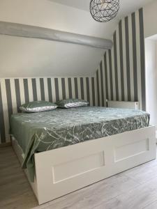 Veneux-les-SablonsMAISON VENEUX LES SABLONS-FONTAINEBLEAU-MORET SUR LOING的一间有条纹墙的房间里一张白色的床