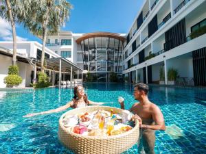 普吉镇The Pago Design Hotel Phuket-SHA Plus的男人和女人在游泳池里吃一篮子食物