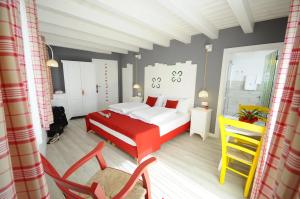Romallo马家宾馆的卧室配有红色和白色的床和椅子