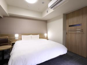 广岛Dormy Inn Hiroshima Annex的卧室配有白色的床和木门