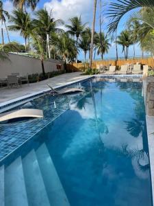塔曼达雷Residencial Taormina - apartamento à beira-mar novinho!的一座拥有蓝色海水和棕榈树的游泳池