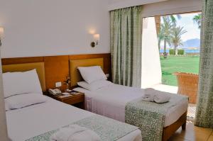 达哈布Dahab Lagoon Club & Resort Ex Tirana Dahab的酒店客房设有两张床和大窗户。