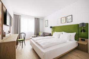 维也纳Bio-Hotel Schani Wienblick的卧室配有一张白色大床和绿色床头板