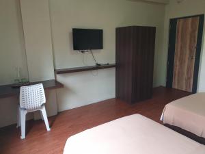 马尼拉OYO 1011 First Hotel的客房设有两张床、一台电视和一把椅子。