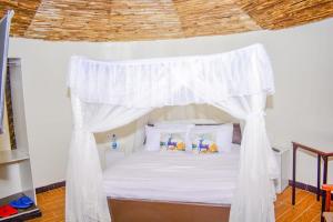 NarokOLOIRIEN HOTEL & RESORT的卧室配有带枕头的白色天蓬床