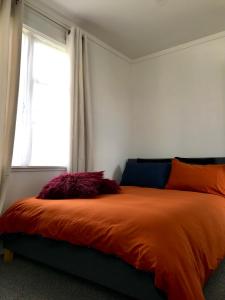 奥克兰Santos Place的一间卧室配有一张带橙色棉被的床和窗户