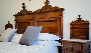 MiciglianoABBAZIA SS. QUIRICO E GIULITTA的一张带木制床头板和白色枕头的床