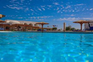 马萨阿拉姆Beach safari nubian resort的一座带蓝色水和遮阳伞的大型游泳池