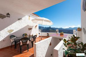 阿尔特纳拉Living Artenara - CAVE HOUSE & TERRACE Adults Only的阳台配有桌椅和遮阳伞。
