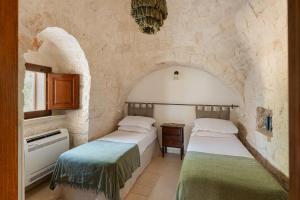 莫诺波利Trullo Due Ulivi的石墙客房的两张床