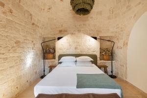 莫诺波利Trullo Due Ulivi的卧室配有一张石墙床
