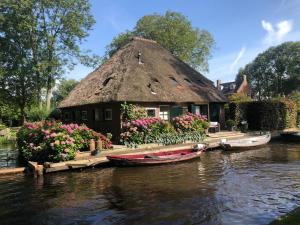 羊角村Plompeblad Guesthouse Giethoorn的茅草屋顶的房子和水面上的船只