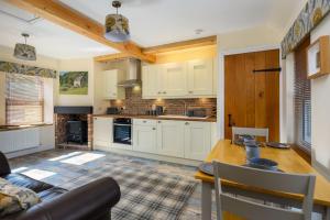 圣安德鲁斯Country Cottage by St. Andrews的厨房配有白色橱柜和木桌