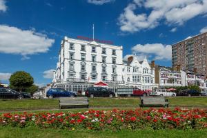 滨海绍森德Muthu Westcliff Hotel (Near London Southend Airport)的花卉公园内长长椅的白色建筑