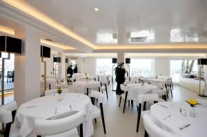 那不勒斯神韵大酒店的用餐室配有白色的桌子和白色的椅子