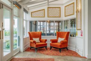 滨海绍森德Muthu Westcliff Hotel (Near London Southend Airport)的走廊上设有两把橙色椅子和窗户