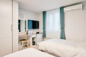 首尔格洛苏吉尔民宿 - 仅限女性的一间卧室配有一张床、一张书桌和一台电视。