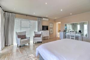开普敦Thyme Wellness Spa and Guesthouse的卧室配有一张白色大床和两把椅子