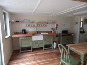 NewchurchNewchurch Nook的厨房配有绿色橱柜和木桌