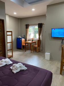 宗通Greathill Gardenhome Resort Chomthong-Chiangmai的客房设有1张床、1张桌子和1台电视。