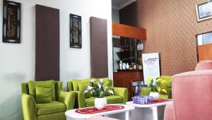 MetroGrand S'kuntum Hotel Syariah的一间设有绿色椅子和桌子的等候室