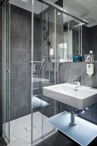 巴塞尔商业酒店的一间带水槽和玻璃淋浴的浴室