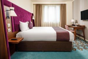 伦敦伦敦桥美居酒店的酒店客房设有一张大床和紫色床头板