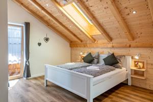 GaißachWohnung Brauneck的一间带白色床铺的卧室,位于带木制天花板的客房内。