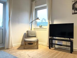 欧登塞One Bedroom Apartment In Odense, Middelfartvej 259的客厅配有椅子和平面电视