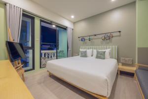 普吉镇Chamemon Bed Phuket Town的卧室配有一张白色大床和电视。