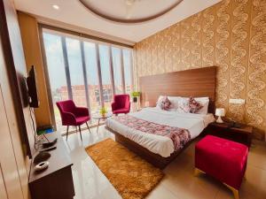 钱德加尔Hotel The Pearl, Zirakpur - A Luxury Family Hotel的一间卧室配有一张大床和红色椅子