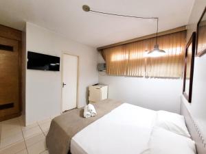 塔瓜汀加Hotel Alvorada Taguatinga - Antigo Hotel Atlantico的卧室配有白色的床和电视。