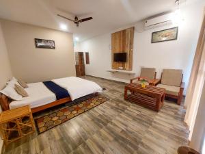 塔拉Grand Narmada Homestay Resort-Bandhavgarh的一间卧室配有一张床、一张沙发和一台电视。