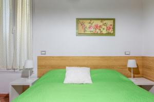 佛罗伦萨Boboli Gardens Lovely Apartment的一间卧室配有绿色的床和两张白色的桌子