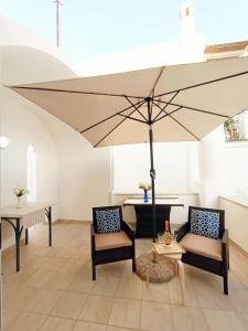 阿纳卡普里L'Archetto romantic suite in the center of Anacapri的一把大伞,放在带椅子和桌子的房间