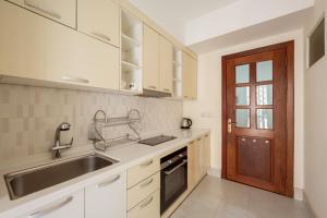 金边E＆V公寓的厨房配有白色橱柜、水槽和门
