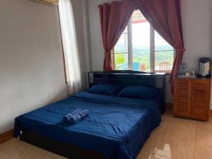 Ban Khao Ya Nua查克民宿的一间卧室配有一张带蓝色床单的床和一扇窗户。