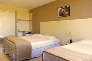 巴西利亚大使酒店的酒店客房设有两张床,墙上挂着一张照片。