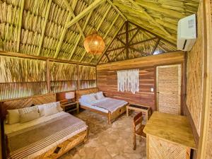 穆库拉岛Hotel Isla Mucura的一间位于稻草小屋内的房间,配有两张床和一张桌子