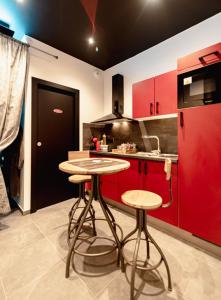 勒米尔蒙spa de la quarterelle LOVE ROOM 88 VOSGES的一间厨房,配有红色橱柜和两个酒吧凳子