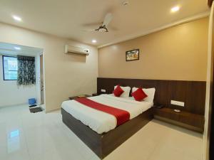 艾哈迈达巴德Hotel Palav Palace的一间卧室配有一张带红色枕头的大床