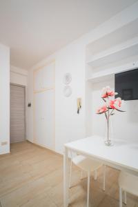 代森扎诺-德尔加达Suite "Castello" del Garda - APT per coppie Garda的白色的用餐室配有白色的桌子和粉红色的鲜花