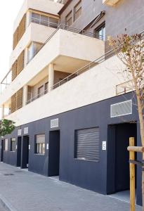 阿尔巴塞特Urbanlux Olimpia Familiar的蓝色建筑,建筑前有两扇车库门