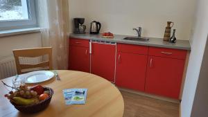 SchalkauFerienpark Thüringer Wald的厨房配有红色橱柜和一张带一碗水果的桌子