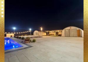拉斯阿尔卡麦Desert Breeze Cocoon的夜间带游泳池的大型停车场